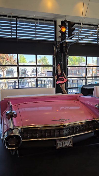 Pink car bed in a room with a traffic light and a cutout of a girl.