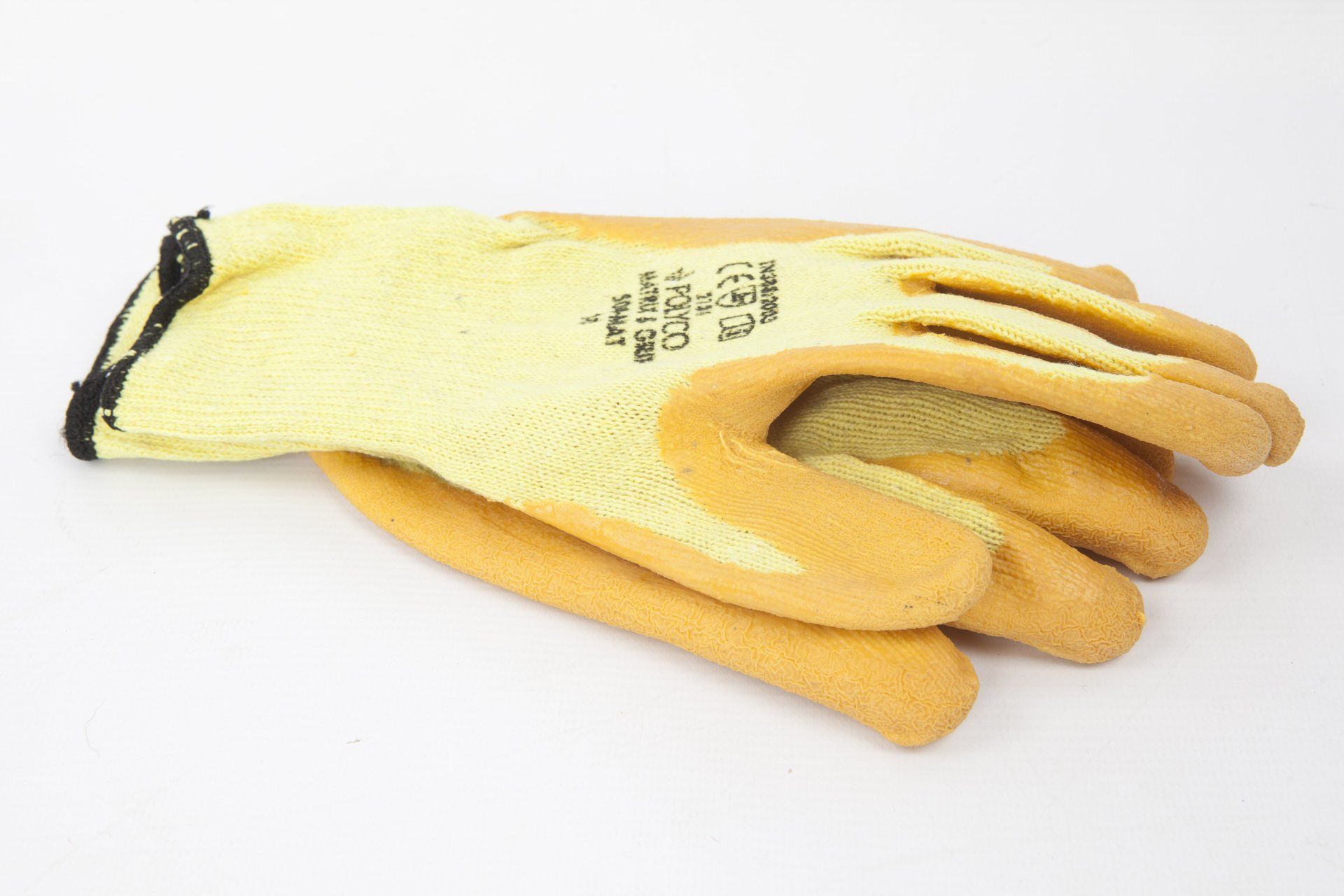 A pair of yellow gloves are stacked on top of each other on a white surface.