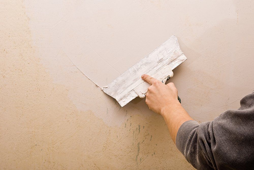 A person is plastering a wall with a spatula.