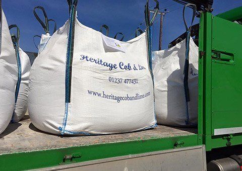 A green truck with a bunch of bags on the back of it.