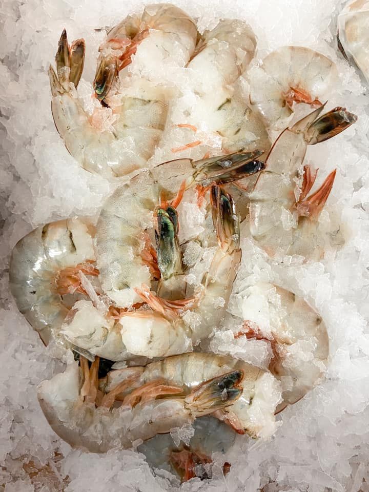 A pile of raw, translucent shrimp nestled on a bed of crushed ice.