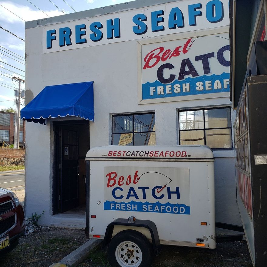 A Best Catch Fresh Seafood shop with a branded white trailer parked outside in front of the building.