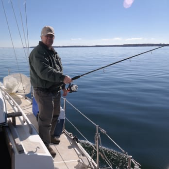 Two landscapers spread black mulch over landscape fabric in a residential front yard near a parked utility vehicle.
