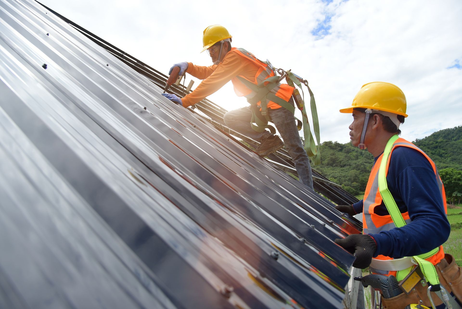 Two men in orange safety vests and helmets repairing a roof, representing Four Seasons Roofing & Rep