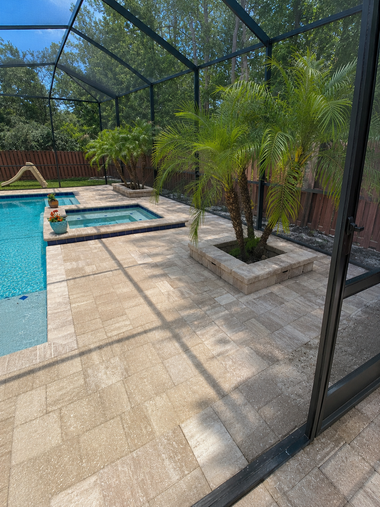 Backyard pool and hot tub under a screened enclosure with potted palms and patio tiles