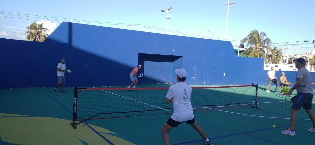 A group of people are playing pickleball on a court.  at the Playa Del Carmen Pickleball Club in Playa Del Carmen, Mexico