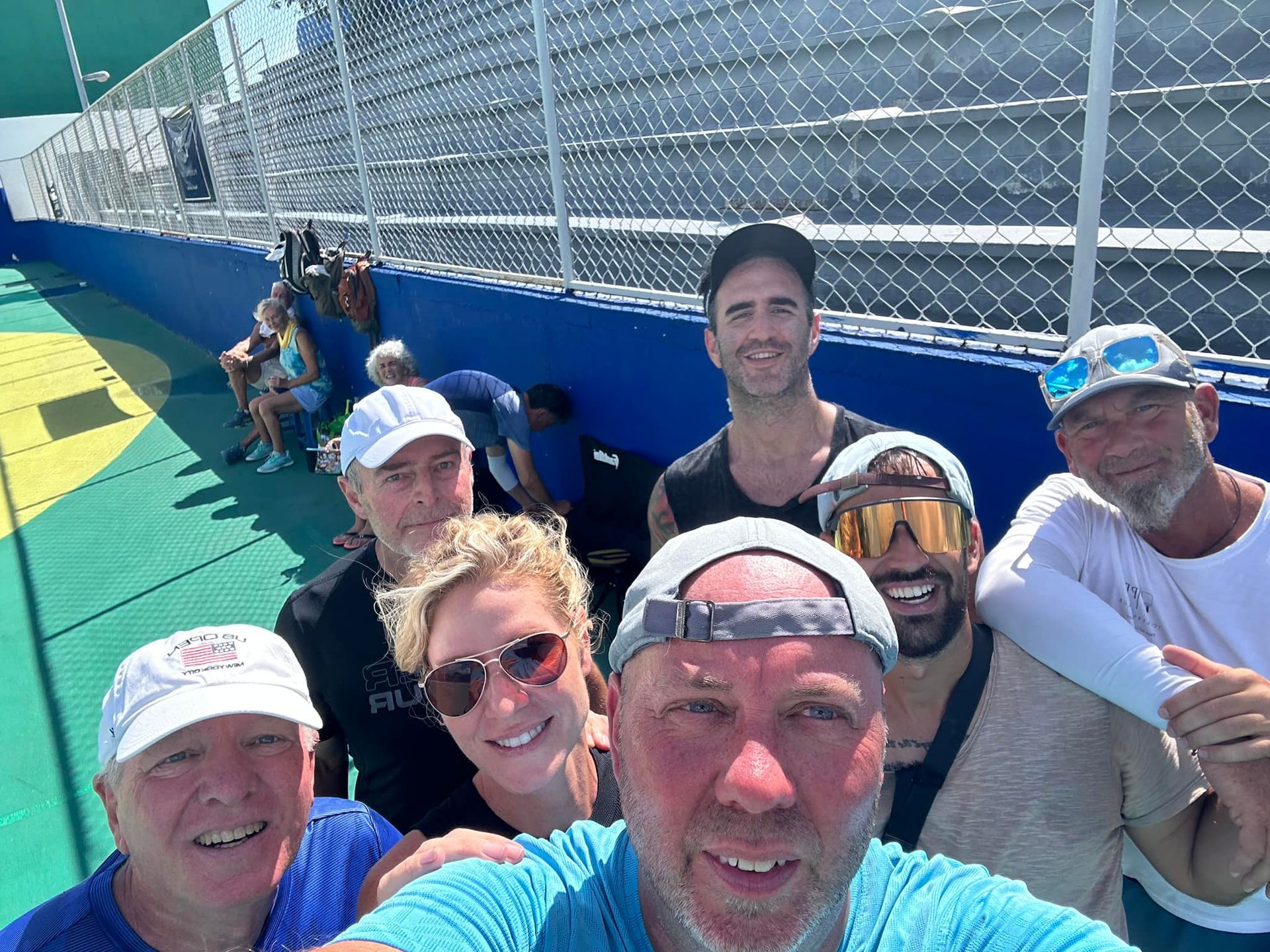 A group of people are posing for a selfie in front of a fence.