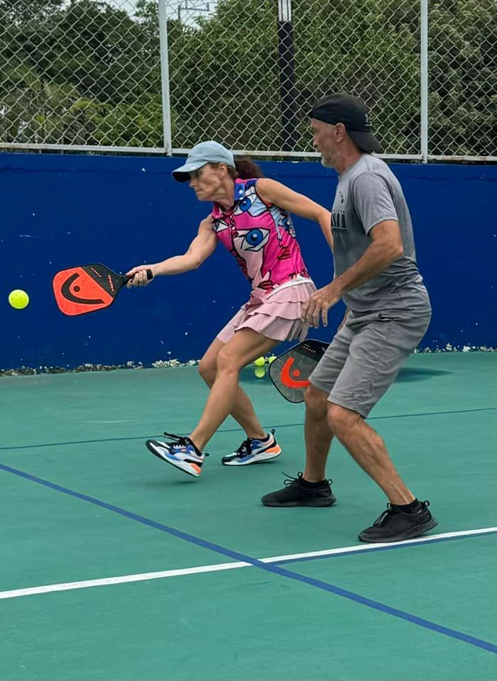 A man and a woman are playing pickleball on a court