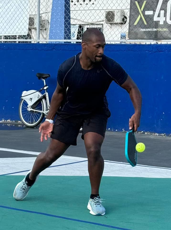 A man is playing pickleball on a court with a sign that says x-40 in the background  at the Playa Del Carmen Pickleball Club in Playa Del Carmen, Mexico