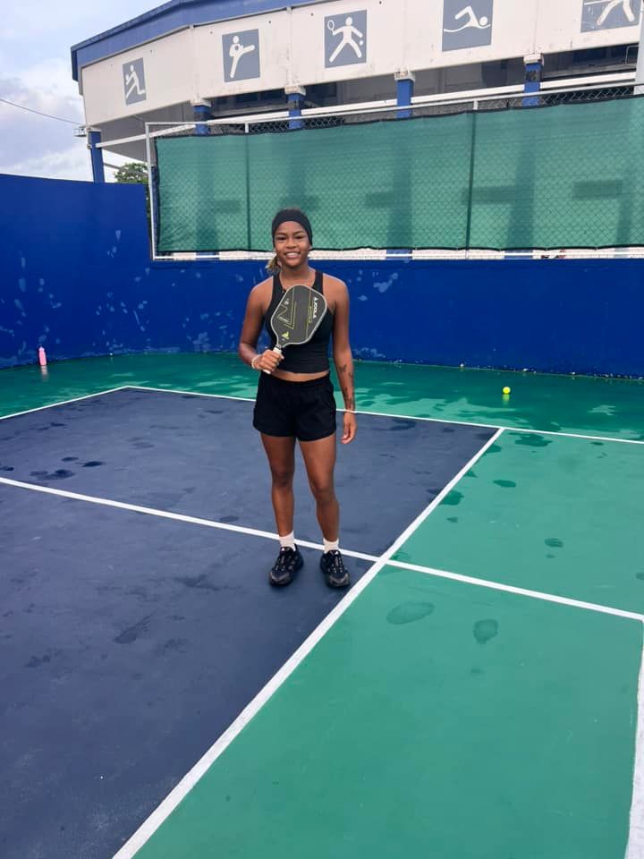 A woman is holding a pickleball racquet on a pickleball court