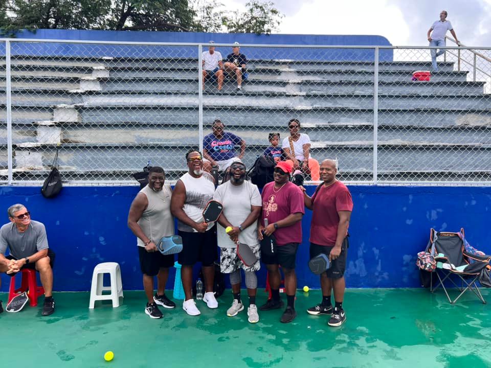 A man with a prosthetic leg is standing next to another man on a tennis court.
