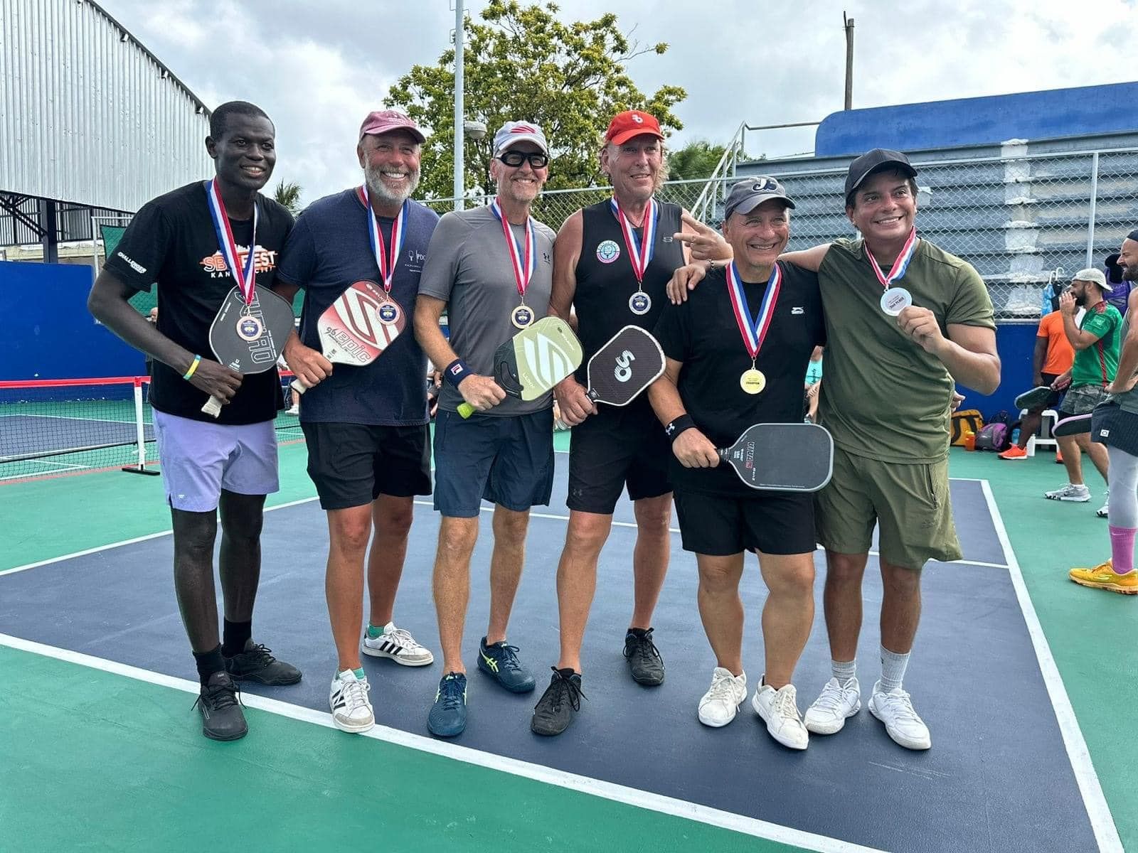 A group of people posing for a picture on a pickleballcourt