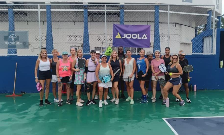 A group of people are posing for a picture on a pickleball court.
