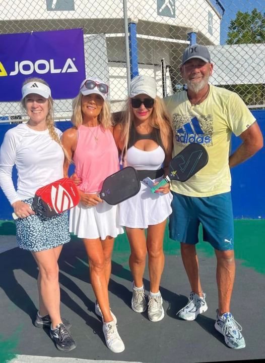 A group of pickleball players.  posing for a picture in front of a joola sign  at the Playa Del Carmen Pickleball Club in Playa Del Carmen, Mexico