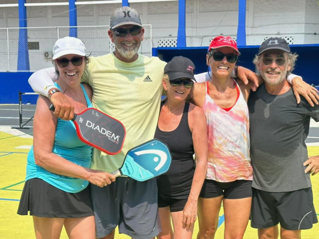 A group of people are posing for a picture and one of them is holding a paddle that says diadem