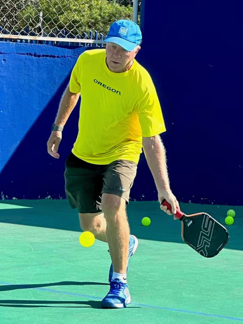 A man in a yellow shirt is playing picklball  at the Playa Del Carmen Pickleball Club in Playa Del Carmen, Mexico rackets.