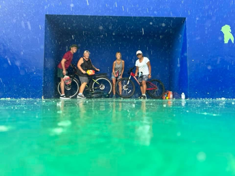 A group of people standing in front of a blue wall with bicycles.