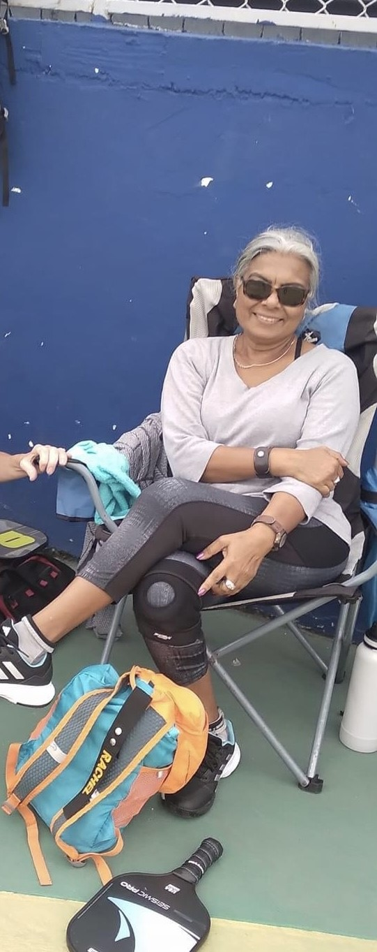 A woman is sitting in a chair next to a backpack.