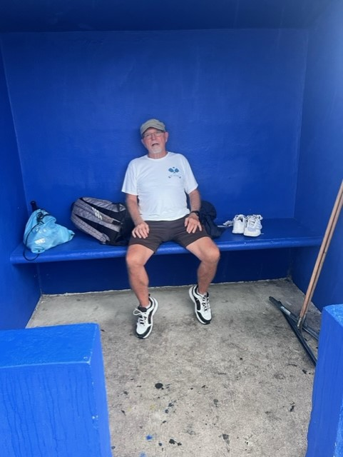 A man sits on a bench in a blue room