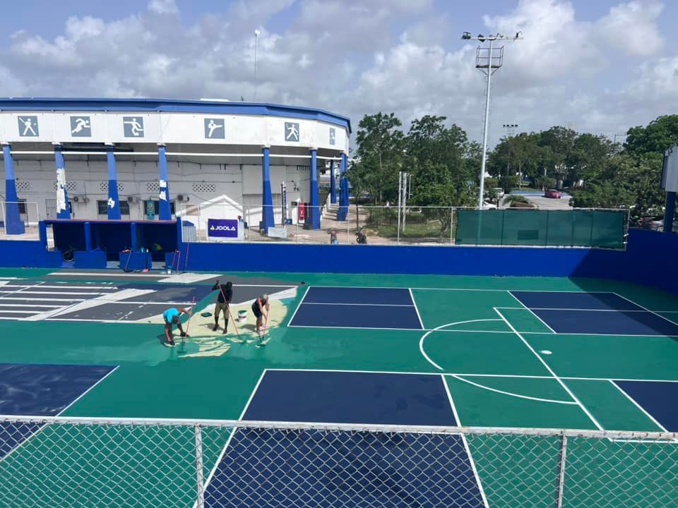 A group of people are working on a pickleball court  at the Playa Del Carmen Pickleball Club in Playa Del Carmen, Mexico rackets.