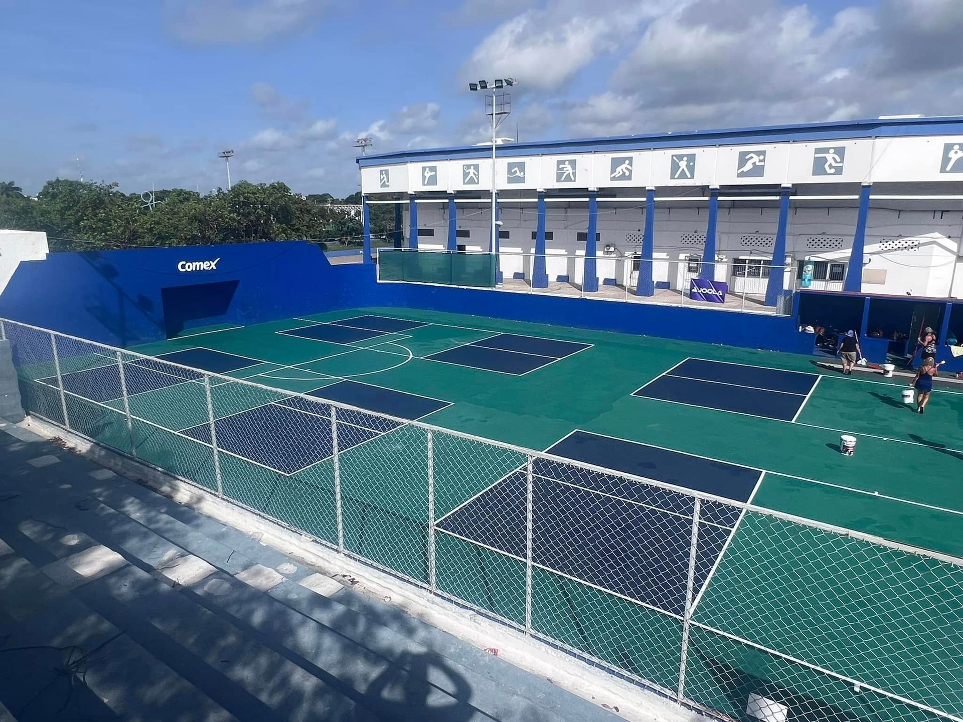 A group of people are working on the Playa Del Carmen Pickle Ball Club pickleball court in Playa Del Carmen, MX