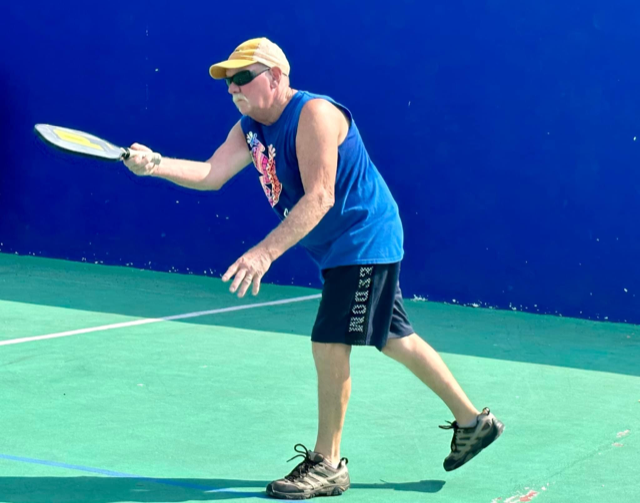 A man wearing a blue tank top and shorts with the word moose on them  at the Playa Del Carmen Pickleball Club in Playa Del Carmen, Mexico