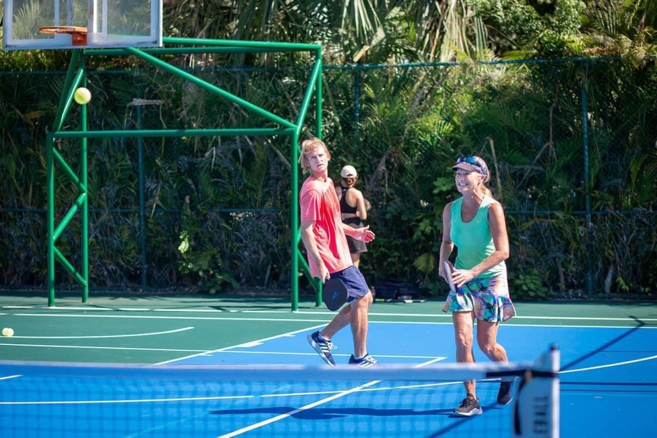 A boy and a girl are playingpickleball on a pickleball court.