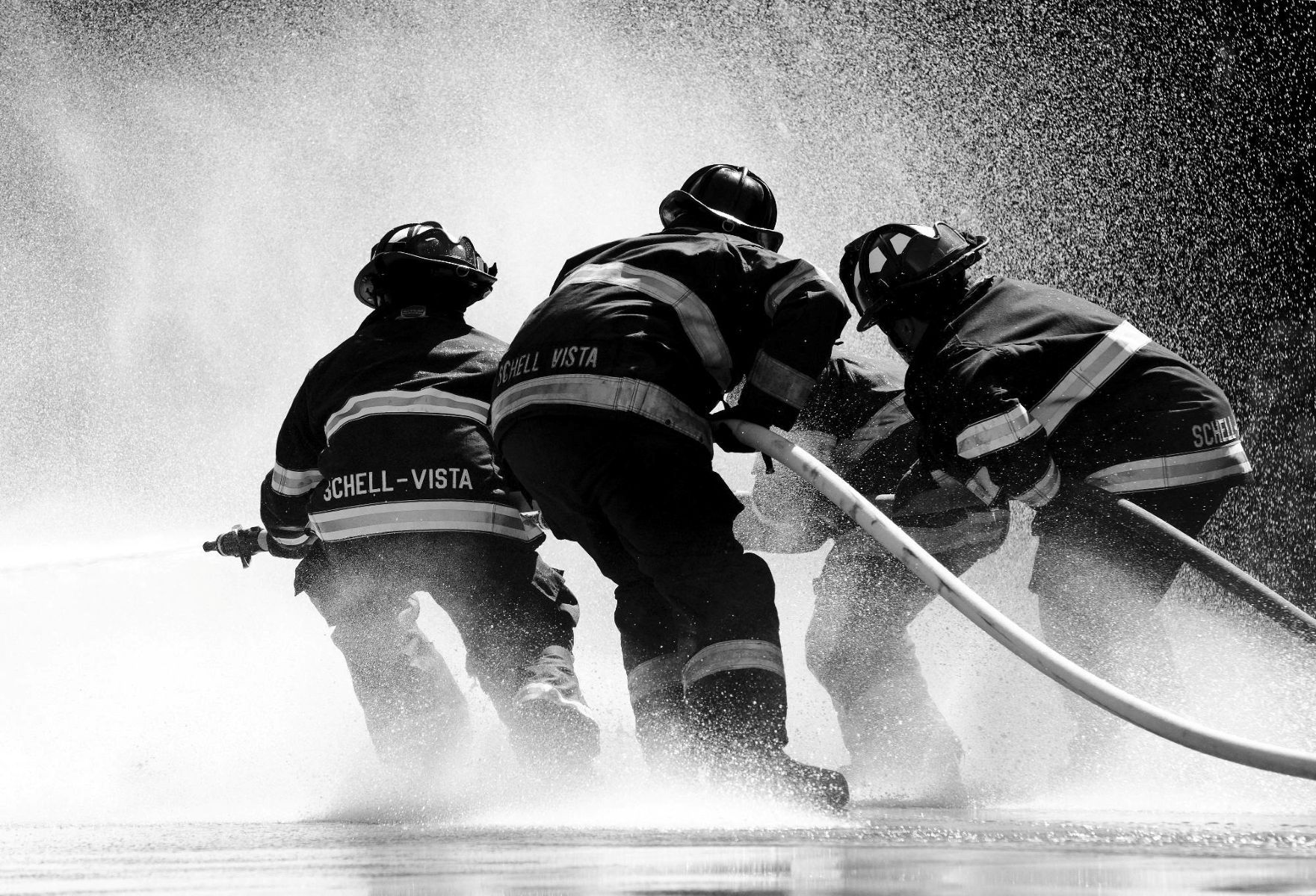 Image of firemen pulling on a hose.