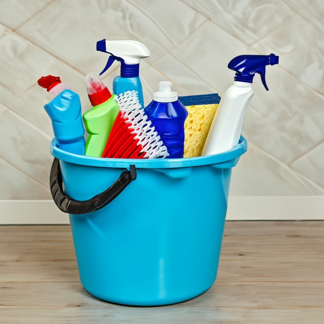 A blue bucket filled with cleaning supplies including spray bottles and sponges