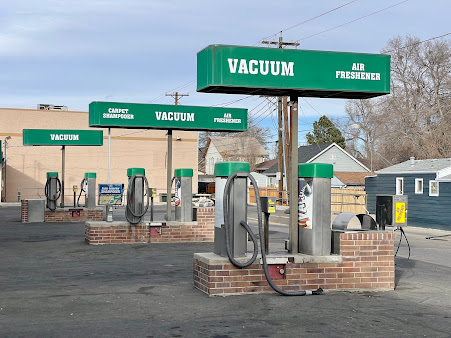 Vacuum cleaner stations at a car wash; green signs and equipment, brick bases.