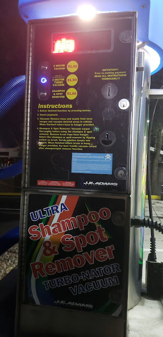 Car vacuum machine with controls, a display, and shampoo/spot remover label.