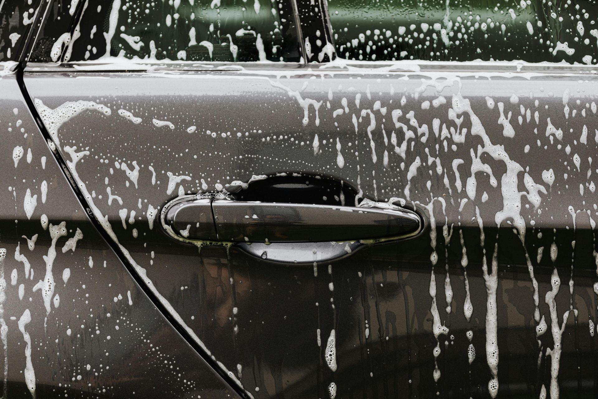 Car door with black handle covered in white soap suds.