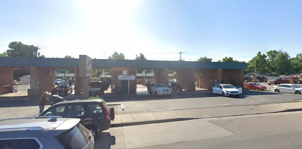 Cars at a gas station, brick columns, and green awning.