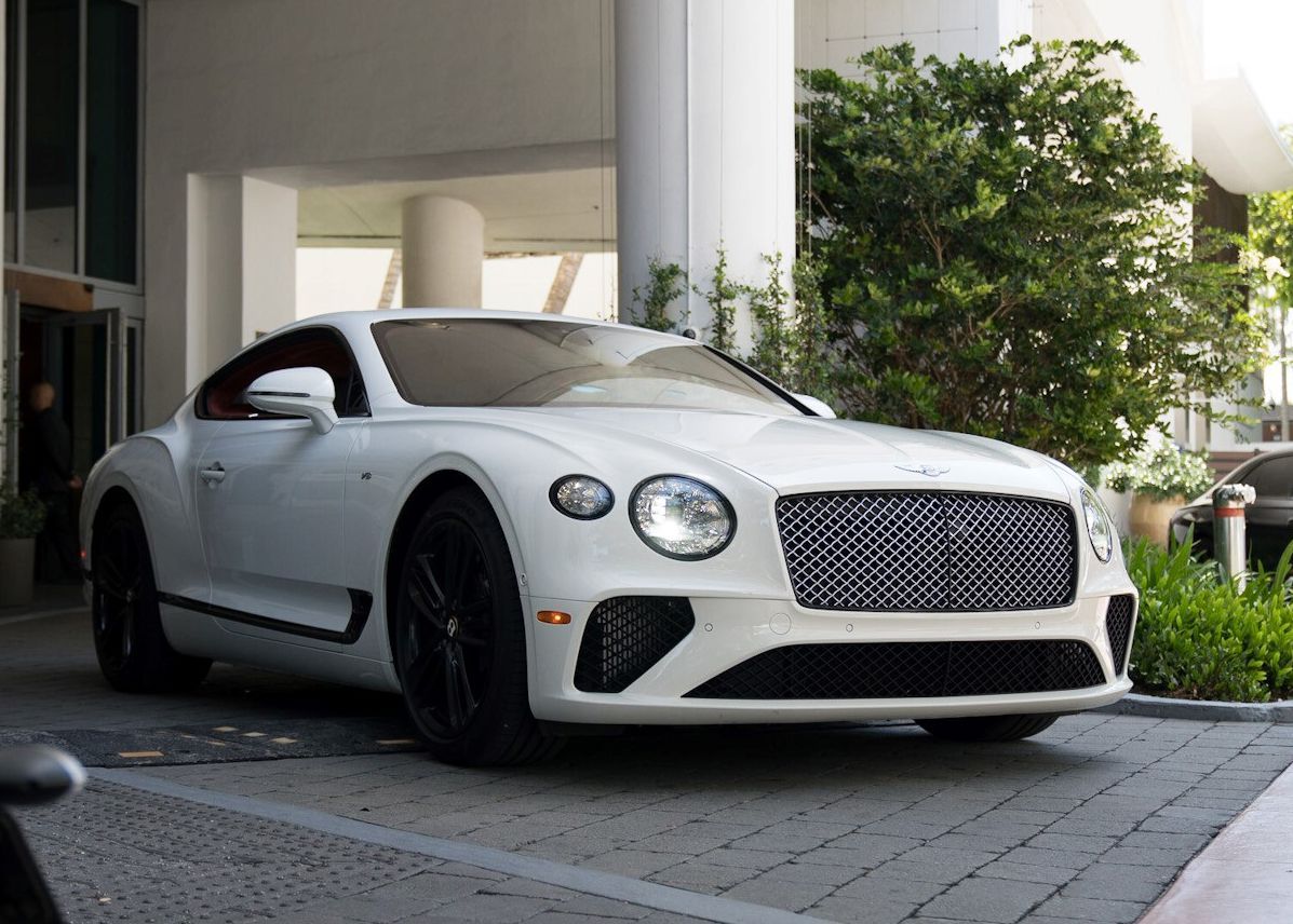 A white Bentley Continental GT is parked in front of a building.