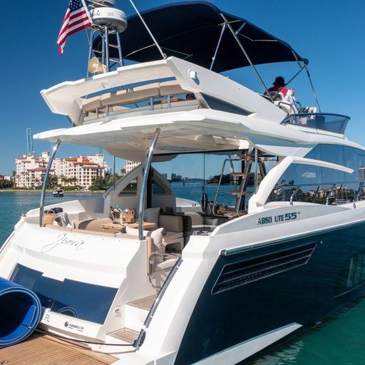 A large white and blue yacht with a flag on top is docked at a dock.