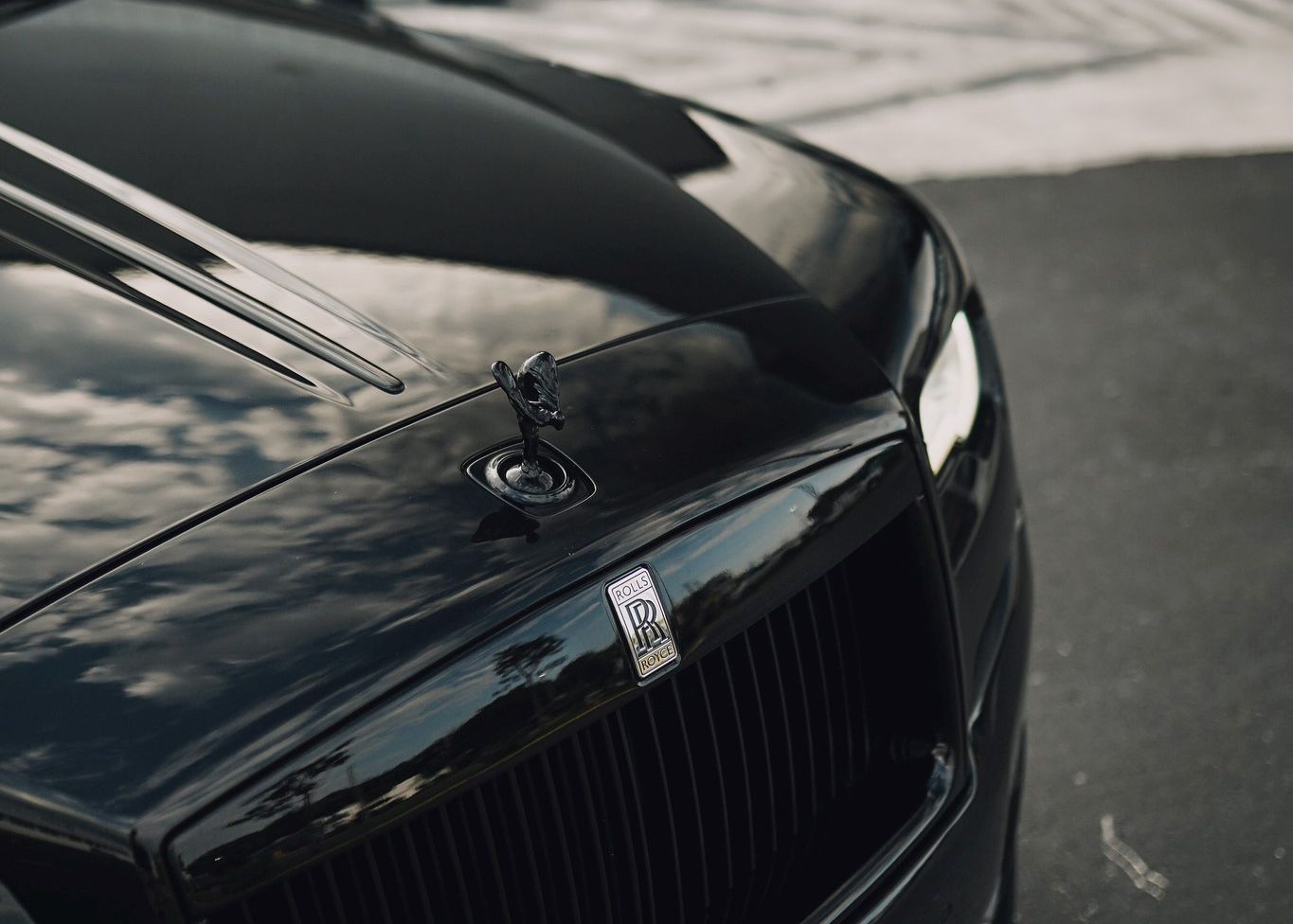 A close up of the hood of a black Rolls Royce parked on the street.