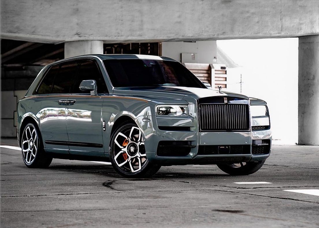 A gray Rolls Royce Cullinan is parked in a parking garage.