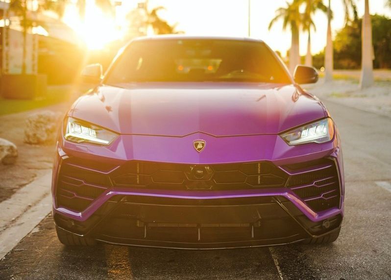 A purple Lamborghini Urus is parked on the side of the road.