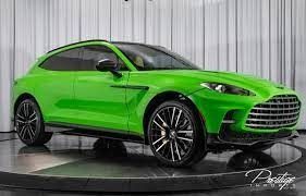 A green Aston Martin DBX is sitting on top of a showroom floor.