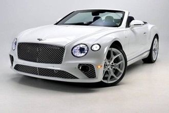 A white Bentley convertible is parked on a white surface.