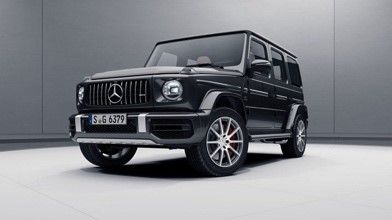 A black Mercedes Benz G63 AMG is parked in a white room.