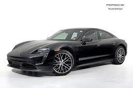 A black Porsche Taycan is parked on a white surface.