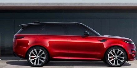 A red Range Rover is parked in front of a garage.