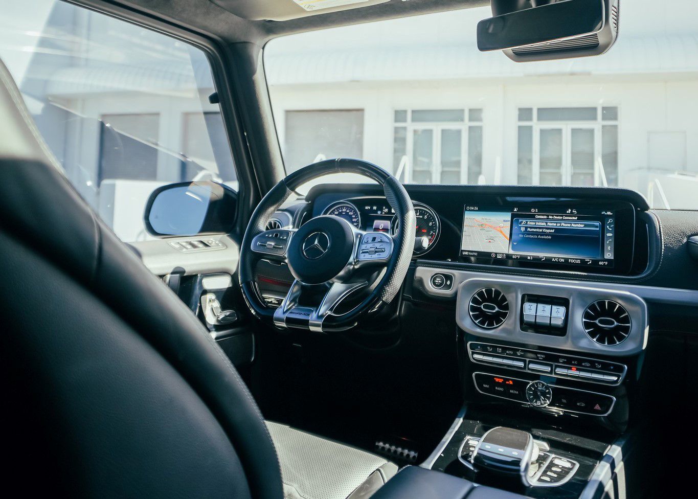 The interior of a Mercedes Benz G550 with a steering wheel and dashboard.