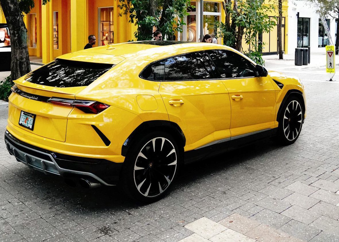 A yellow Lamborghini Urus is parked on the side of the road.