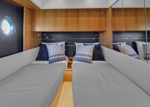 A bedroom on a boat with two beds and a mirror.