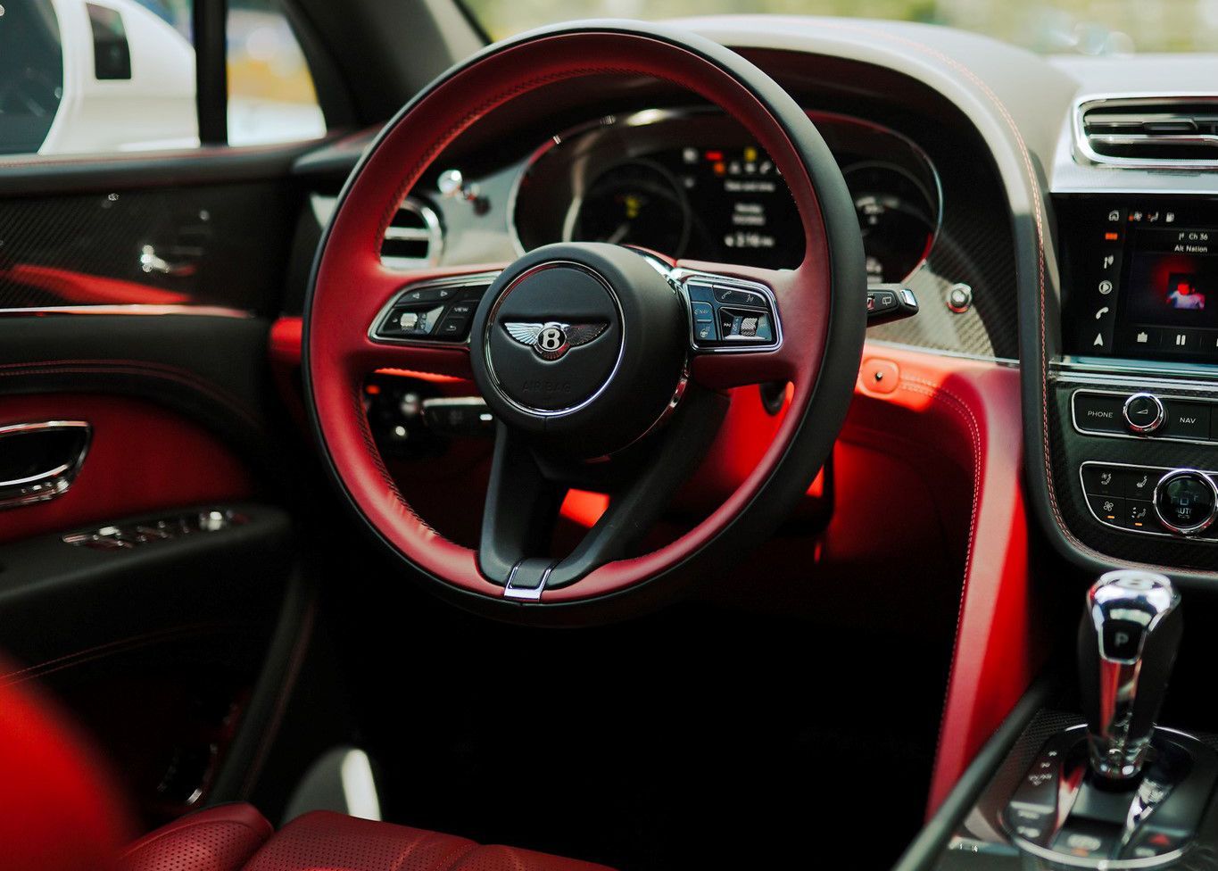 The interior of a Bentley car with a red steering wheel.