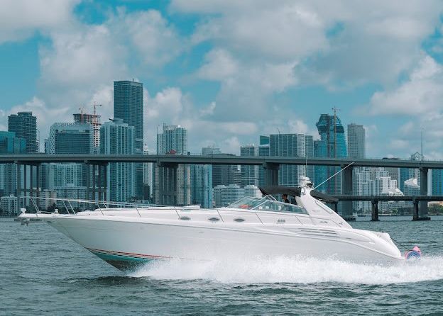 A white boat is floating on top of a body of water in front of a city skyline.