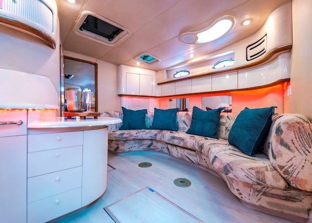 A living room on a boat with a couch and blue pillows.