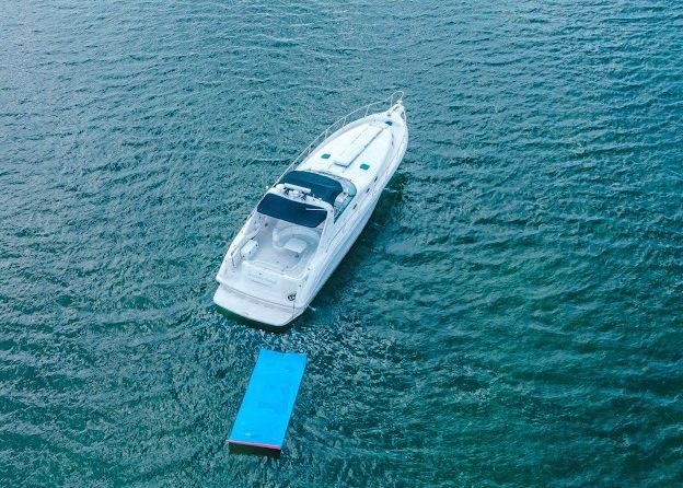 A white boat is floating on top of a blue raft in the water.